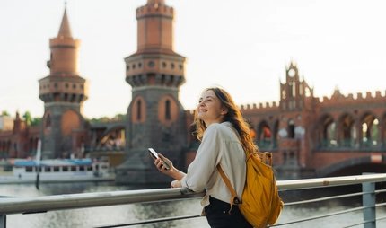 Junge Frau mit Smartphone vor der Oberbaumbrücke