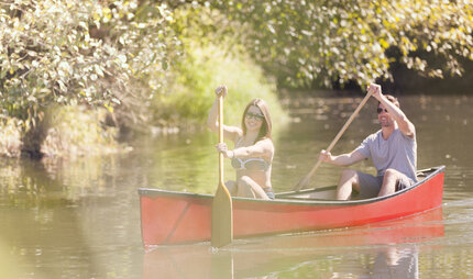 Couple rowing canoe on river