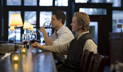 Two men sitting at a bar in Berlin drinking wine 