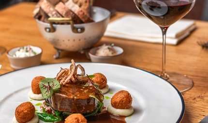 Rinderhirschfilet mit gebratenem Kalbsbries und Bratensoße, serviert mit Rotwein im Gourmet-Restaurant