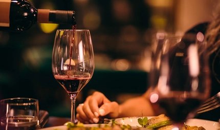 Nahaufnahme eines Sommeliers beim Servieren von Rotwein in einem gehobenen Restaurant