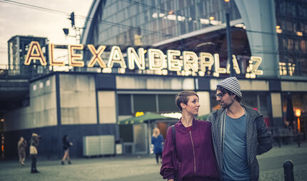 Young couple in front of the Alexanderplatz S-Bahn station at dusk