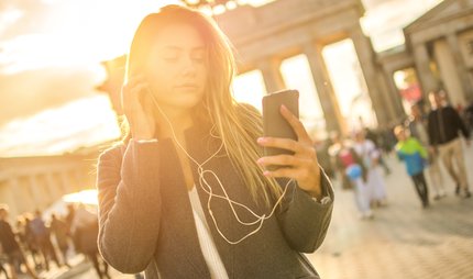 Junge Frau hört Audiotour am Brandenburger Tor.