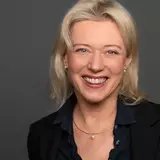 Person mit langem Haar lächelt in die Kamera.