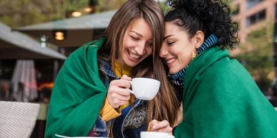 Gemeinsam unter einer Decke: Freundinnen trinen Kaffee in Berlin